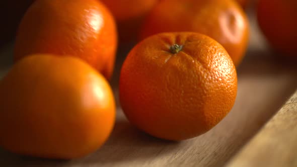 Slow motion footage of fresh, ripe clementines dropping and rolling on a wood cutting board