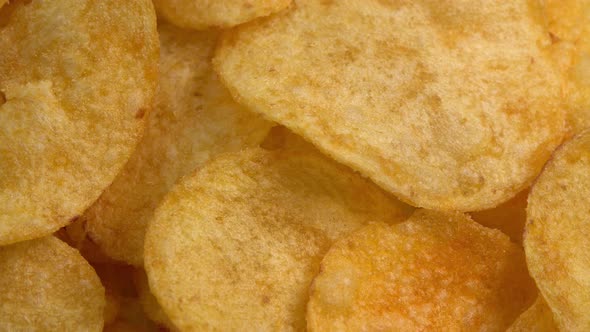 Crispy potato chips rotating in macro. Golden fried potatoes close up. Potato snack for unhealthy