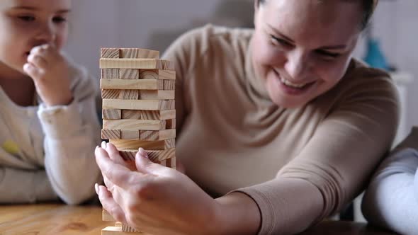 Happy mom playing with children in game. parent helps to build tower of blocks.