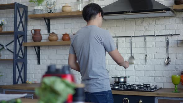 Back View of Young Asian Man Mixing Food in Pan in Slow Motion