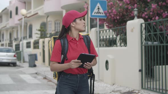 Female Courier with Thermal Backpack Using Tablet