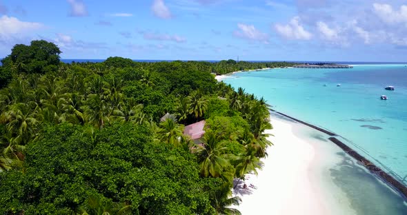 Wide angle drone tourism shot of a white sandy paradise beach and blue sea background in vibrant 4K