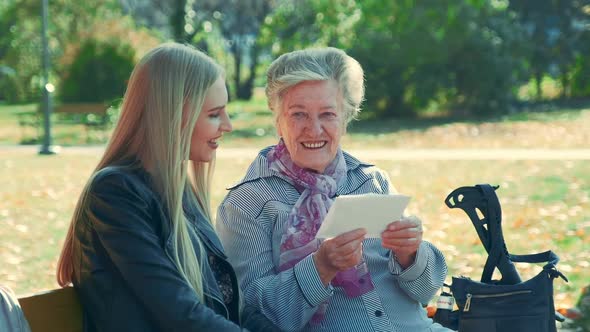 Middle Close Up of Old Woman Reading a Letter to Pretty Young Woman in Park