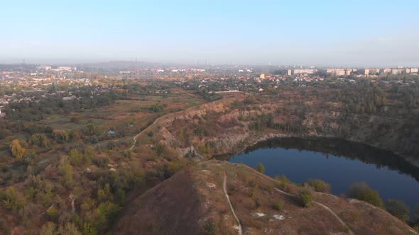 Pull Away Aerial Shot of Blue Calm Lake and Hills Around Covered with Greenery