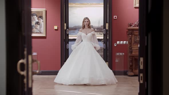 A Blonde Woman with Styled Hair Wearing Wedding and Walks Through the Museum