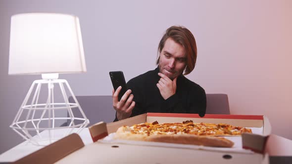 Young Man Having a Video Call with Family After Having Pizza for Dinner