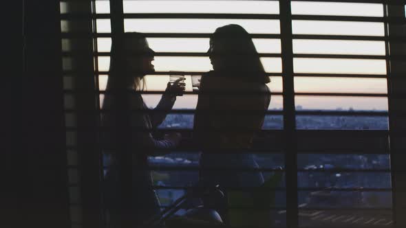 Two girls cheering and drinking on the balcony