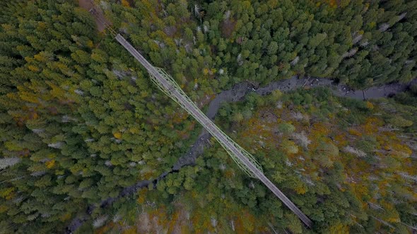 Aerial top down rotating footage of an old and abandoned bridge spanning across a creek.