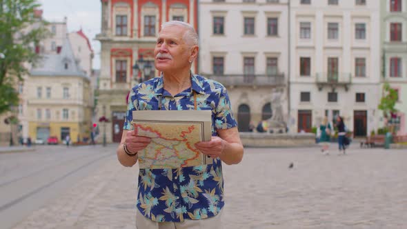 Elderly Stylish Tourist Grandfather Man Walking Along Street Looking for Way Using Paper Map in City