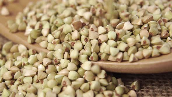 Buckwheat falls on a wooden spoon on burlap