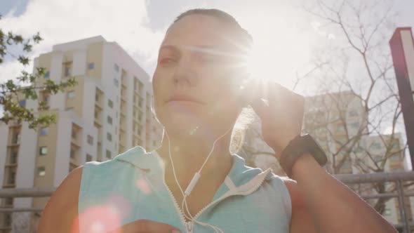 Sporty Caucasian woman putting her headphones on outdoor