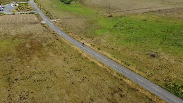 Fixed shot Of Two Persons Running On Road In Middle Of Green Beautiful Field, California