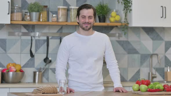 Young Man Smiling at the Camera While Standing in Kitchen