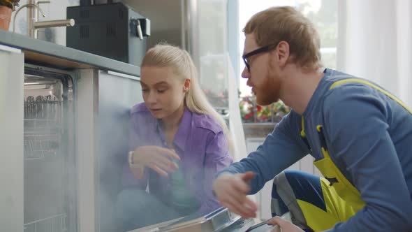 Plumber Installing New Dishwasher and Talking To Housewife