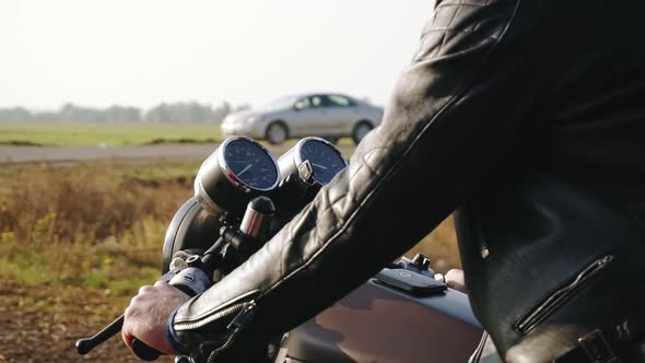 Side View of a Man in Black Helmet and Leather Jacket Riding Motorcycle on a Asphalt Road in the