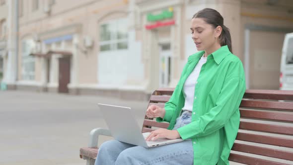 Coughing Hispanic Woman Using Laptop While Sitting Outdoor on Bench
