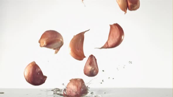 Super Slow Motion Garlic Cloves Fall on the Water with Splashes
