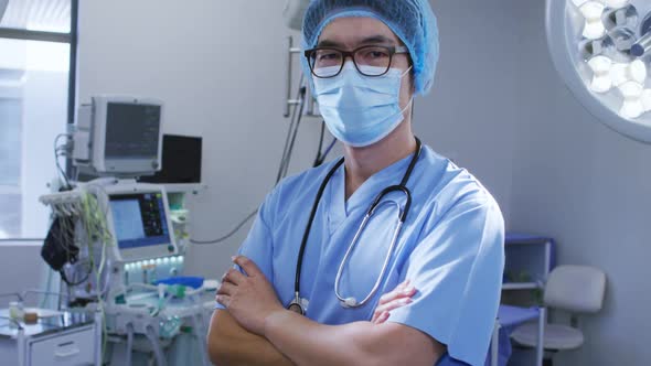 Portrait of male asian surgeon wearing face mask and scrubs in hospital