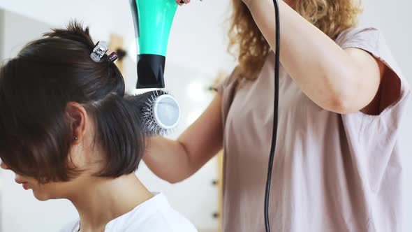 Hairdresser Making Hairstyle with Hairdryer to Client in Beauty Salon Slomo