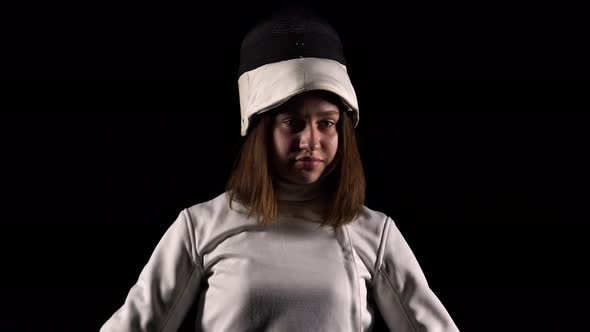 Portrait of Confident Young Woman Fencer Looking Into the Camera on Black Studio Background