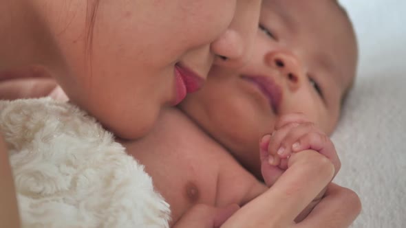 Young mother with newborn baby in bed at home