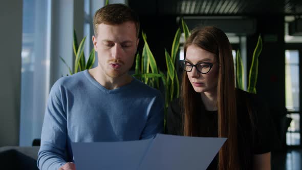 Two Colleagues Study the Company's Development Schedules in the Office