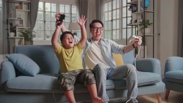 Asian Man And Son Win Playing Video Game, Hands Up While Winning Video Game