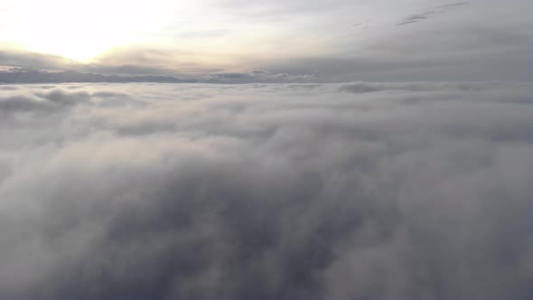 Incredible Aerial View Shot Above Swirling Fog and Clouds at Sunset in the Mountains