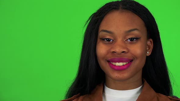 A Young Black Woman Smiles at the Camera - Face Closeup - Green Screen Studio