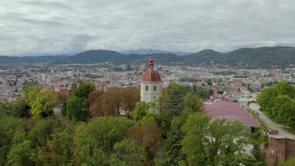 Aerial view flying away from Glockenturm tower on Graz's Schloßberg hilltop woodland park