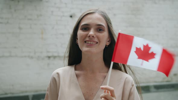 Slow Motion Portrait of Cute Young Female Student Holding Canadian Flag Outdoors on Brick Wall