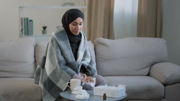 Sick Young Woman in Black Hijab Wrapped Herself in Blanket Sit on Couch in Living Room Ill Islamic