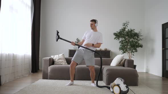 Excited Young Guy Pretending To Be Playing Guitar On Vacuum Cleaner