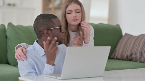 Mixed Race Couple Reacting to Loss While Using Laptop at Home