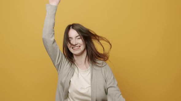 Woman Smiling Dancing to Music Rhythmically to Beat Moving on Yellow Background