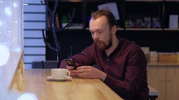 A man use smartphone, drink coffee.