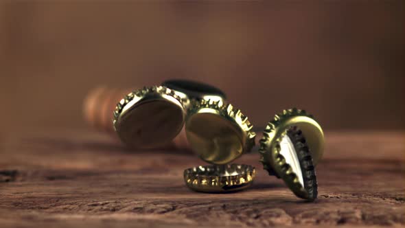 Super Slow Motion Lids From Beer Bottles Fall on a Wooden Table