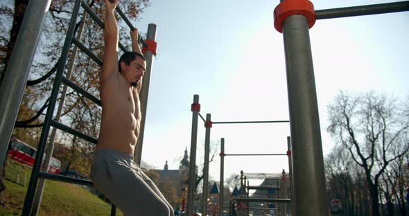 A Man Is Hanging on the Ladder and Lifting His Legs in Good Weather 