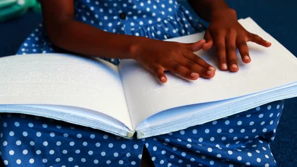 Mid section of schoolgirl reading a braille book 4k