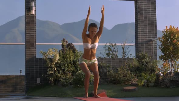 Woman in Shorts Stands in Yoga Pose Bending Knees