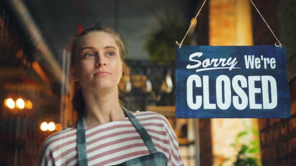 Young Woman Opening Cafe in Morning Hanging We Are Open Sign on Front Door