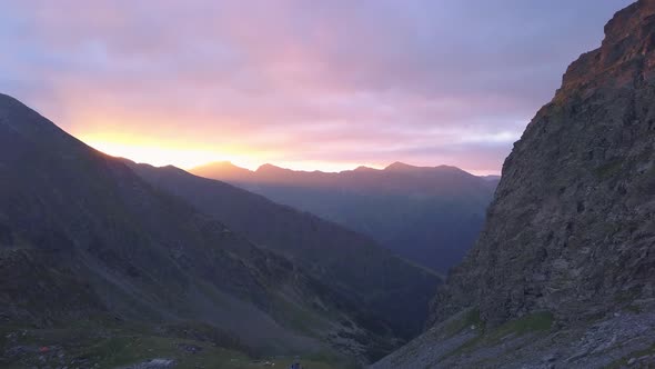 Amazing red and purple sunset sky over distant jagged mountain peaks in the Carpathians. Negoiu Peak