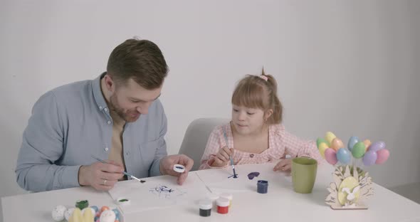 Girl with Down Syndrome Painting Easter Eggs with Father