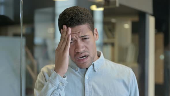 Tired Young African Man Having Headache in Modern Office