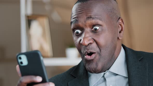 African American Old 50s Surprised Amazed Shocked Man Looking at Mobile Phone Screen Reading