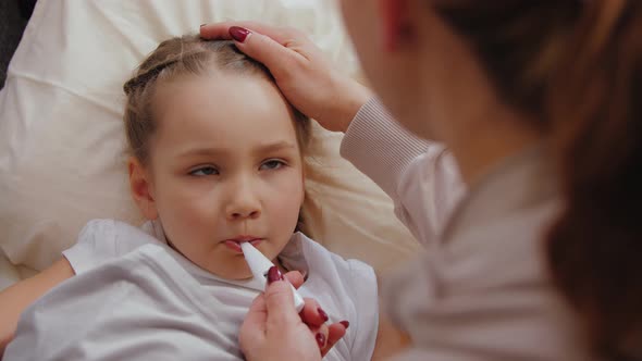 Mother Measuring Temperature of Ill Little Girl Taking Care of Daughter