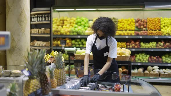 Female Grocery Store Employee in Face Mask and Gloves Checking Freshness of Products in Store