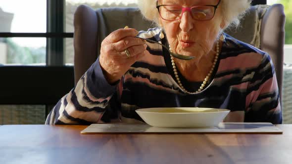 Senior woman having soup on dining table at home 4k