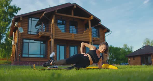 Young Woman is Doing Sports in the Courtyard of Country House