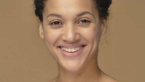 Beauty Portrait of Young African American Woman Turns Towards Camera and Smiles Showing White Teeth